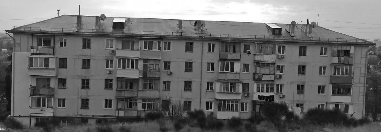 Фасад стандартного пятиэтажного жилого дома «хрущевки» в Севастополе: штукатурка, характерные балконы, вход в подъезд