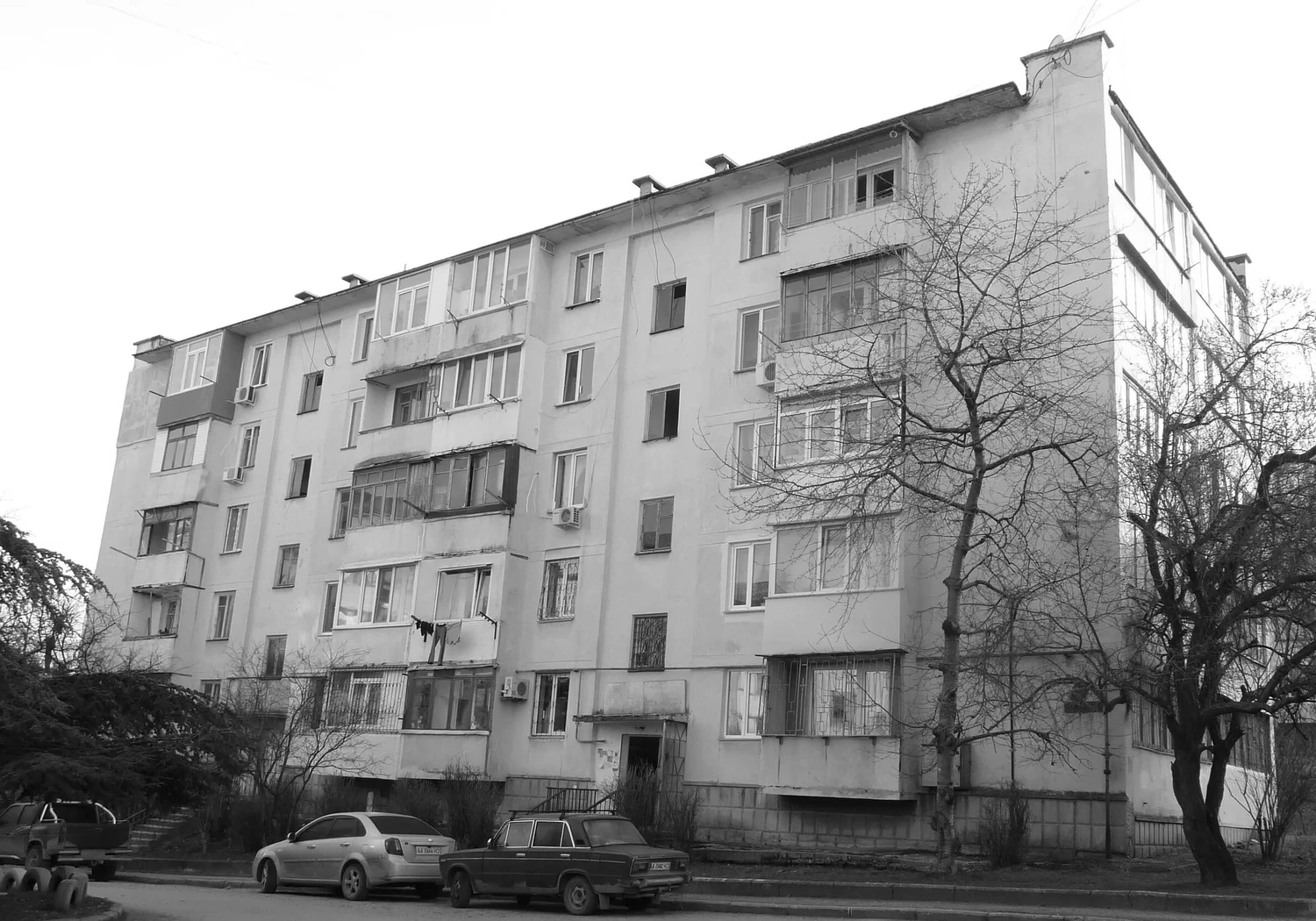 Фасад стандартного пятиэтажного дома-«брежневки» из инкерманского камня в Севастополе: видны лоджии, балконы, входная группа