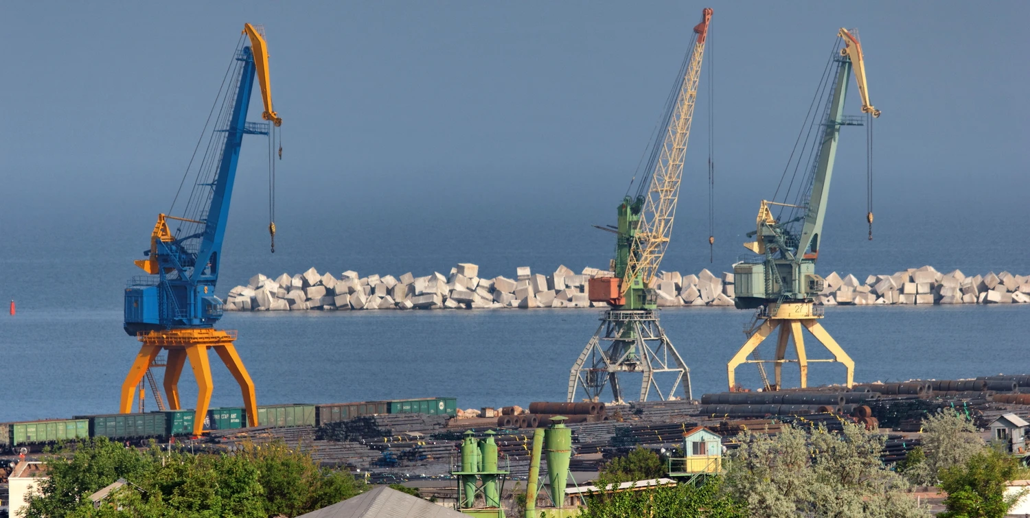 Панорамный вид на прибрежную промышленную зону в бухте Камышовой (Севастополь) с портовыми кранами, железнодорожной веткой и производственными ангарами.