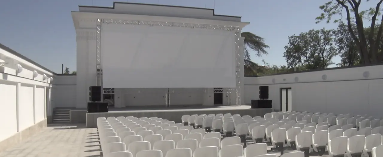 Вечерний киносеанс в открытом кинотеатре на Матросском бульваре Севастополя: зрители на шезлонгах перед большим экраном.